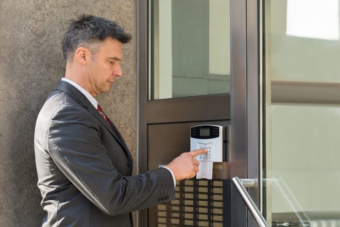 Mature Businessman Using Door Security System On Wall